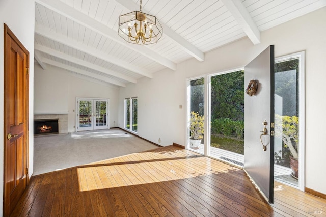 unfurnished living room with vaulted ceiling with beams, baseboards, a chandelier, and wood finished floors