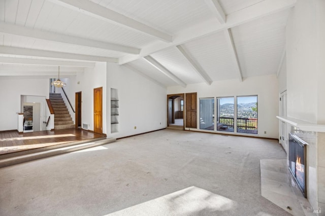 unfurnished living room with baseboards, light colored carpet, stairway, a fireplace, and beam ceiling