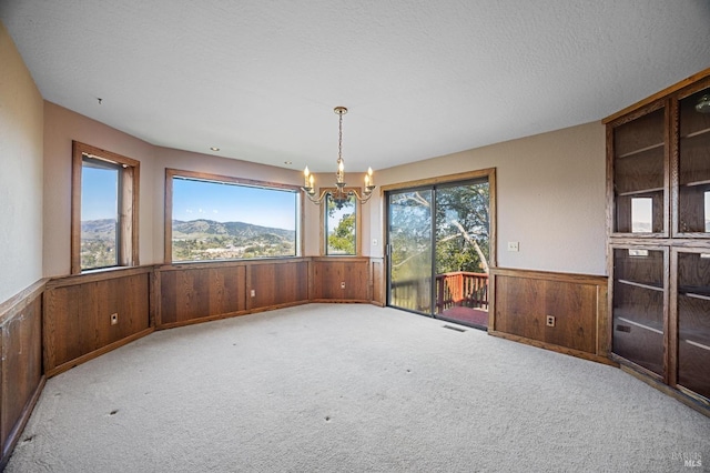 unfurnished room with a wainscoted wall, a mountain view, light colored carpet, and wood walls