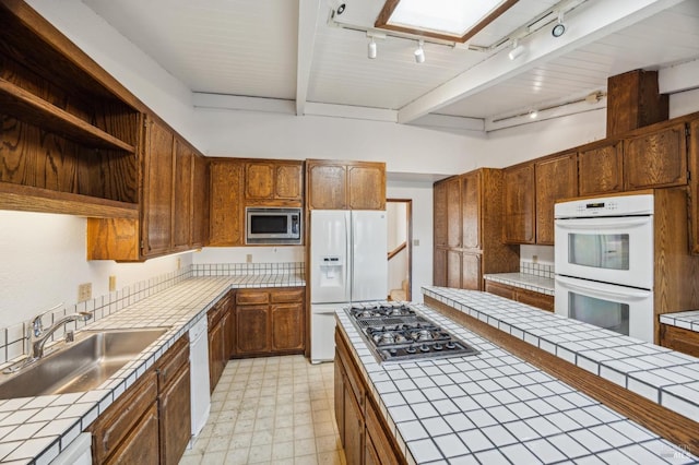 kitchen with tile counters, stainless steel appliances, and a sink