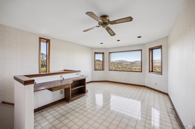 empty room featuring baseboards, ceiling fan, and wallpapered walls