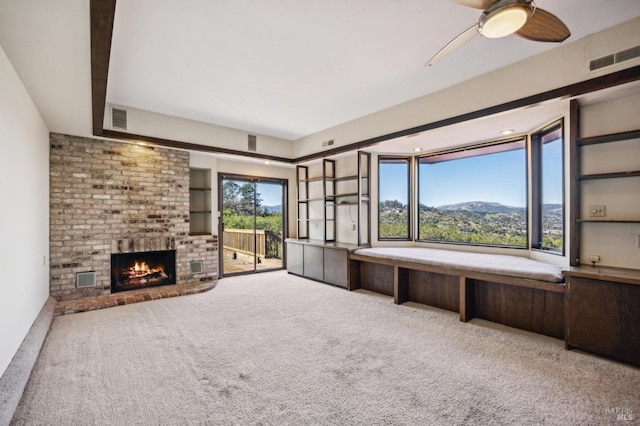 unfurnished living room featuring carpet floors, a brick fireplace, visible vents, and a mountain view