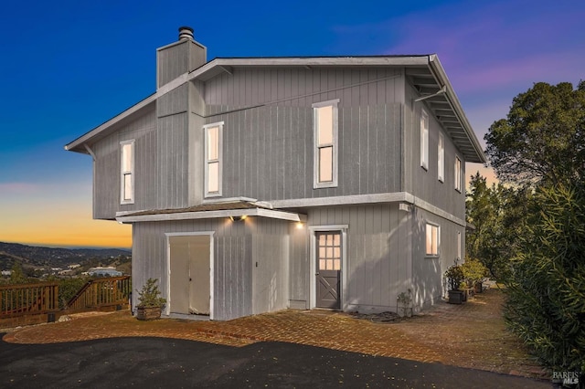 back of house at dusk featuring a chimney