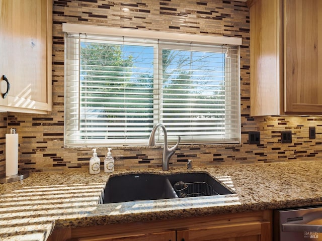 kitchen featuring a healthy amount of sunlight, stone counters, decorative backsplash, and a sink