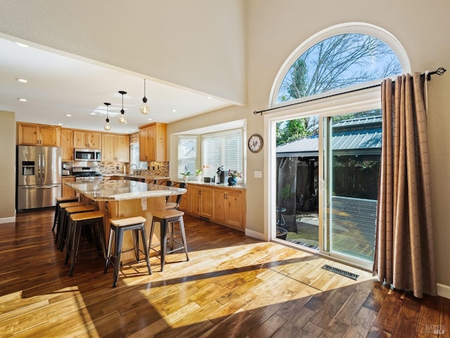 kitchen with a center island, pendant lighting, stainless steel appliances, visible vents, and light wood-style flooring