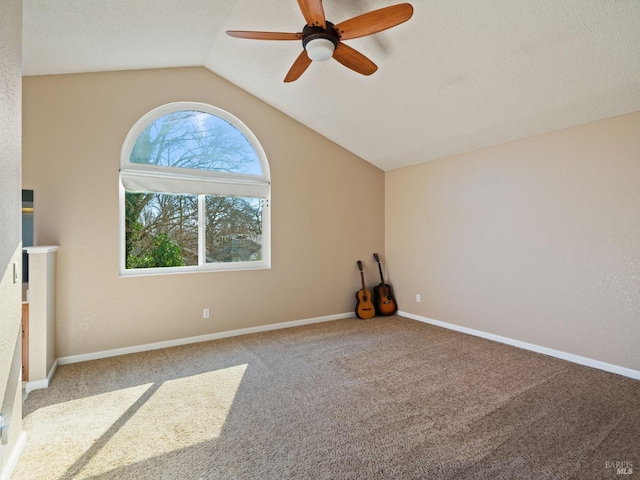 spare room with baseboards, a ceiling fan, lofted ceiling, carpet, and a textured ceiling