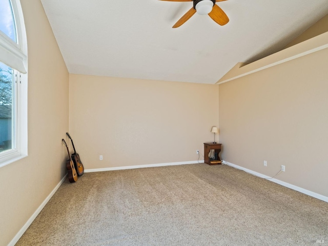 carpeted empty room featuring lofted ceiling, plenty of natural light, baseboards, and ceiling fan