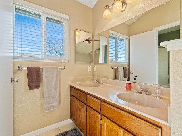 bathroom featuring baseboards, double vanity, a sink, and tile patterned floors