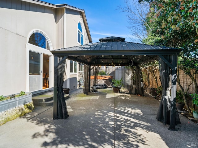 view of car parking with a gazebo, a shed, concrete driveway, and fence