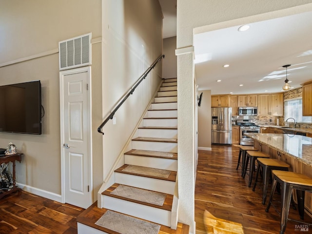 staircase featuring baseboards, visible vents, wood finished floors, and recessed lighting