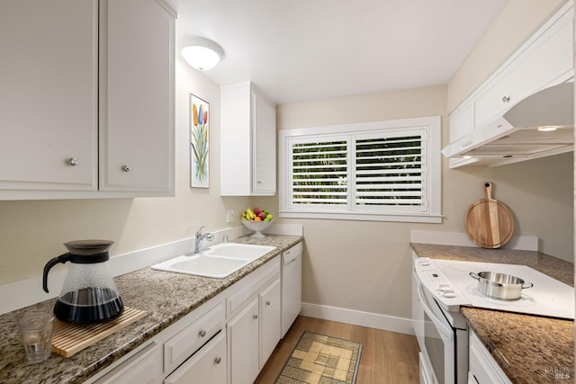 kitchen with white appliances, sink, light wood-type flooring, dark stone counters, and white cabinets