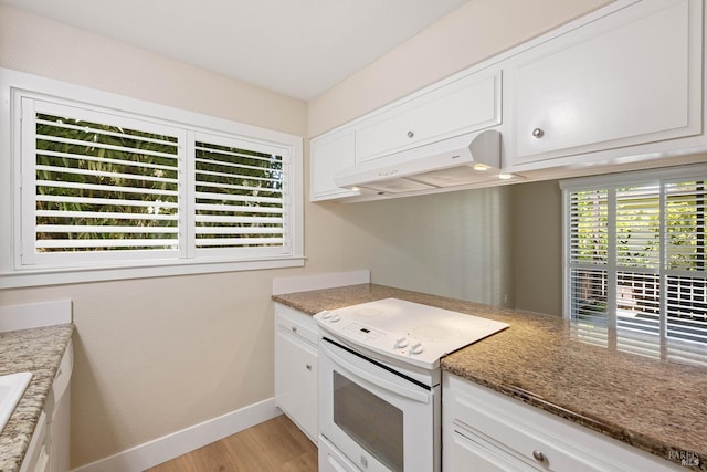 kitchen with extractor fan, white electric stove, white cabinets, and a wealth of natural light