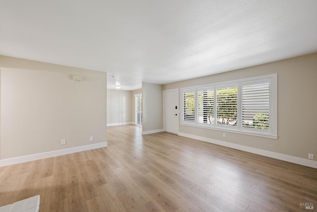 spare room featuring light wood-type flooring and a textured ceiling