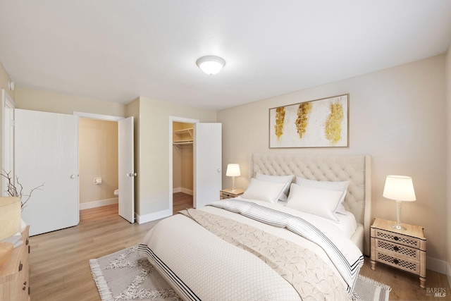 bedroom featuring light hardwood / wood-style flooring, a walk in closet, and a closet