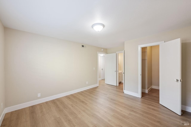 unfurnished bedroom with light hardwood / wood-style floors, a closet, and a spacious closet