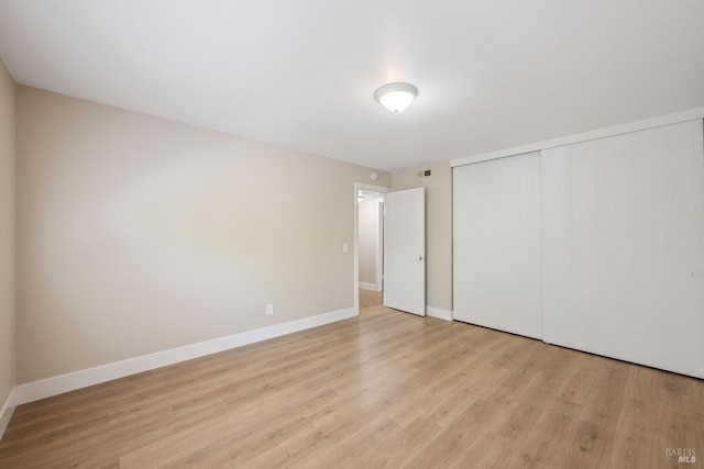 unfurnished bedroom featuring light wood-type flooring and a closet