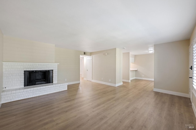 unfurnished living room with a brick fireplace and hardwood / wood-style flooring