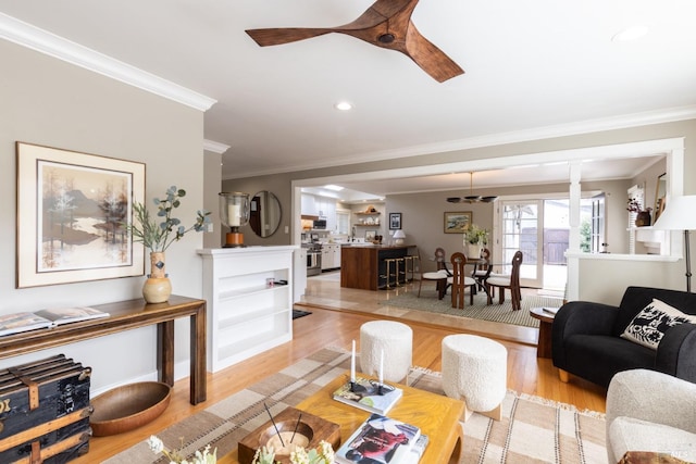 living room with ornamental molding, ceiling fan, and light wood-type flooring