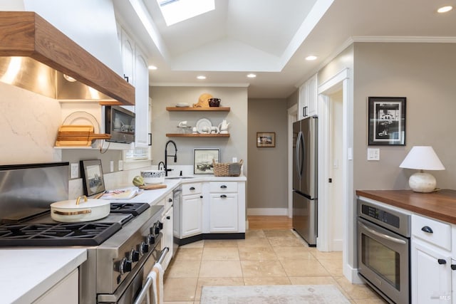 kitchen with white cabinetry, stainless steel appliances, sink, a tray ceiling, and crown molding