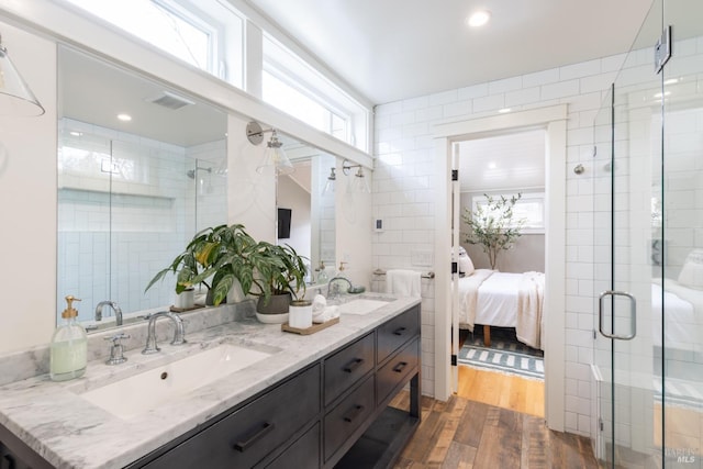 bathroom with hardwood / wood-style flooring, vanity, tile walls, and an enclosed shower