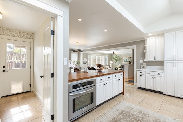 kitchen featuring stainless steel oven, butcher block countertops, vaulted ceiling, ceiling fan, and white cabinets