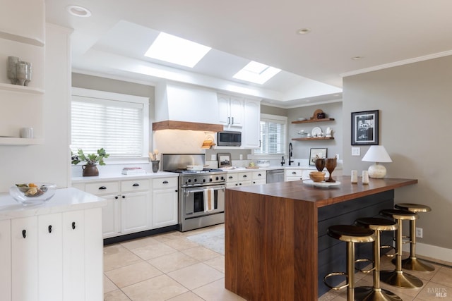 kitchen with white cabinetry, ornamental molding, appliances with stainless steel finishes, and a skylight