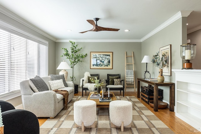 living area with ornamental molding, ceiling fan, and light wood-type flooring