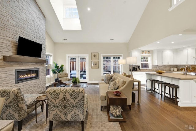 living room featuring plenty of natural light, a fireplace, high vaulted ceiling, and wood finished floors