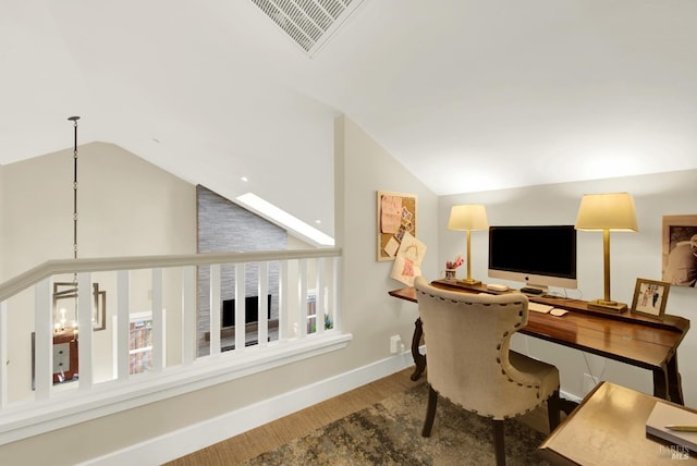 office space featuring baseboards, visible vents, vaulted ceiling, and wood finished floors