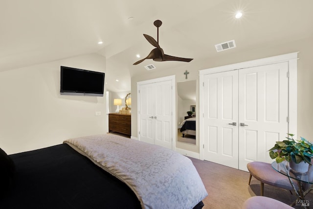 bedroom with vaulted ceiling, carpet floors, visible vents, and multiple closets