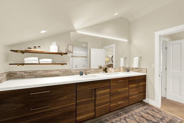 bathroom with double vanity, tasteful backsplash, vaulted ceiling, a sink, and a shower stall