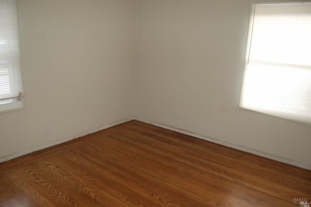 spare room featuring dark hardwood / wood-style flooring and a wealth of natural light