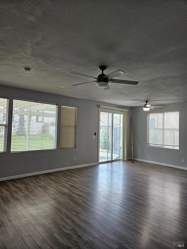 unfurnished room with a textured ceiling, baseboards, and wood finished floors