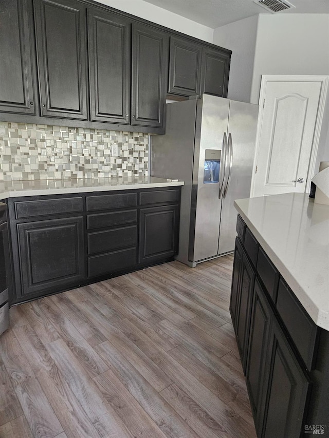 kitchen with decorative backsplash, stainless steel refrigerator with ice dispenser, and light countertops