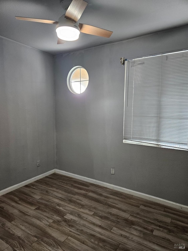 empty room with baseboards, dark wood finished floors, and a ceiling fan