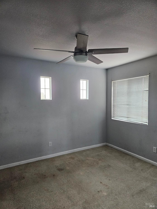 carpeted empty room featuring a ceiling fan, a textured ceiling, and baseboards