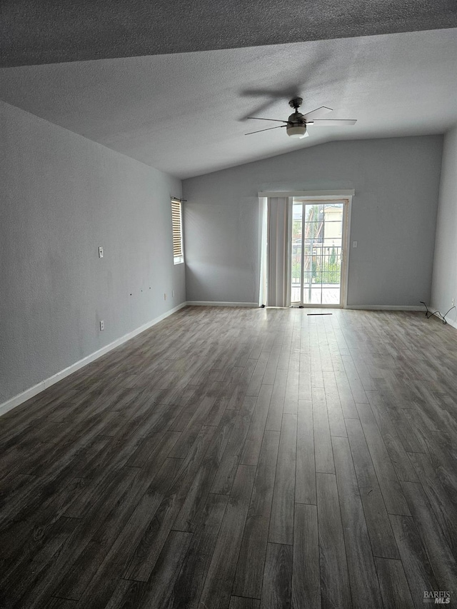 spare room with a textured ceiling, dark wood-type flooring, a ceiling fan, baseboards, and vaulted ceiling