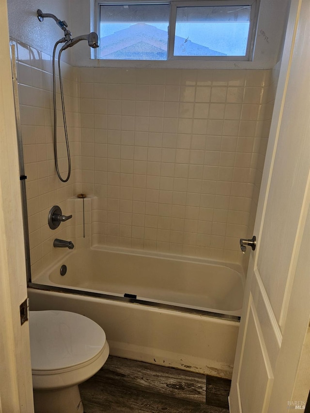 full bath featuring a wealth of natural light, shower / bath combination, toilet, and wood finished floors