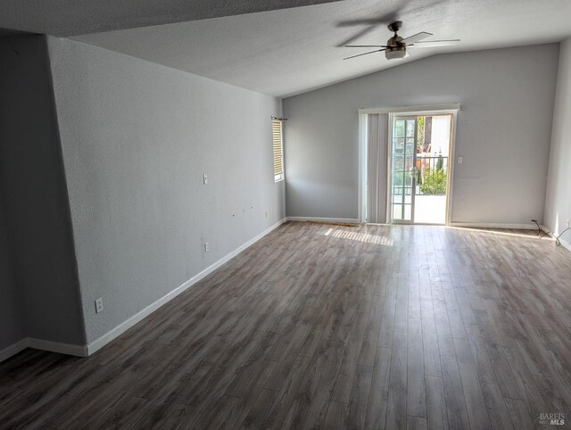 empty room featuring baseboards, ceiling fan, dark wood-type flooring, vaulted ceiling, and a textured ceiling