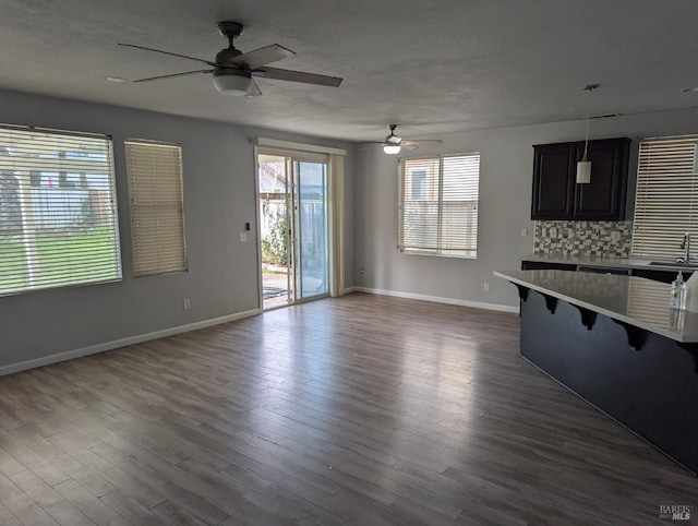 interior space with baseboards, ceiling fan, dark wood-style flooring, a textured ceiling, and a sink