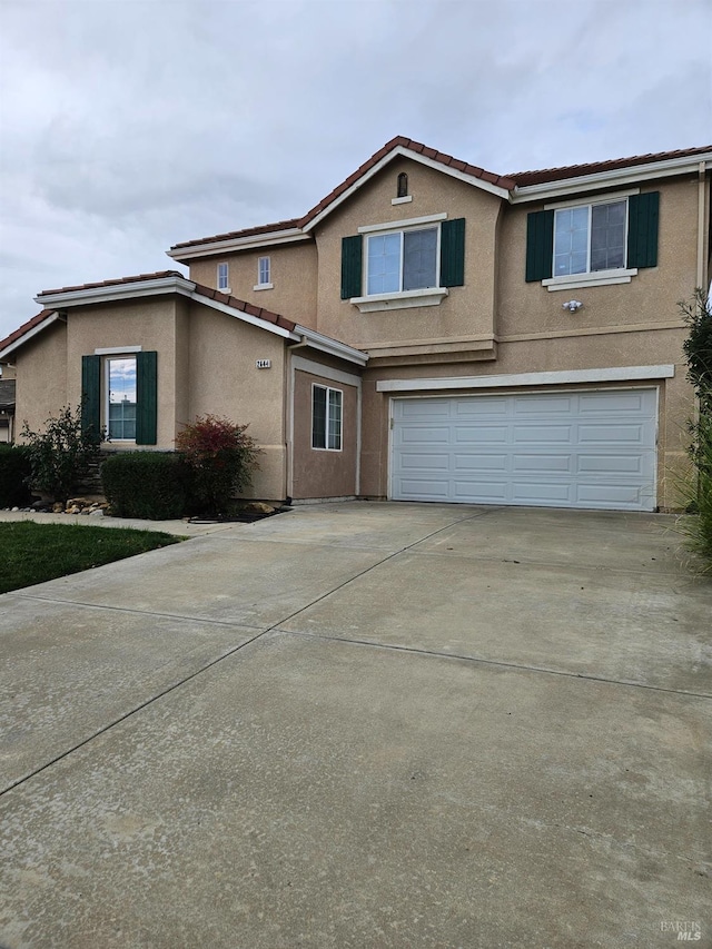 traditional home featuring concrete driveway, a tile roof, an attached garage, and stucco siding