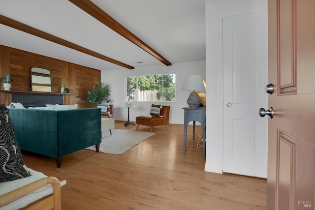 living room with beamed ceiling, wood walls, and light hardwood / wood-style floors