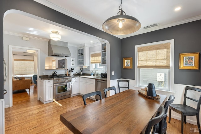 dining area featuring ornamental molding, light wood-style floors, visible vents, and plenty of natural light