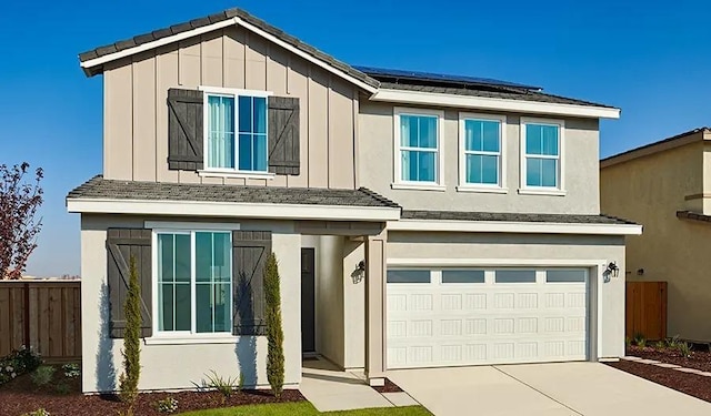 traditional home with board and batten siding, fence, roof mounted solar panels, concrete driveway, and an attached garage