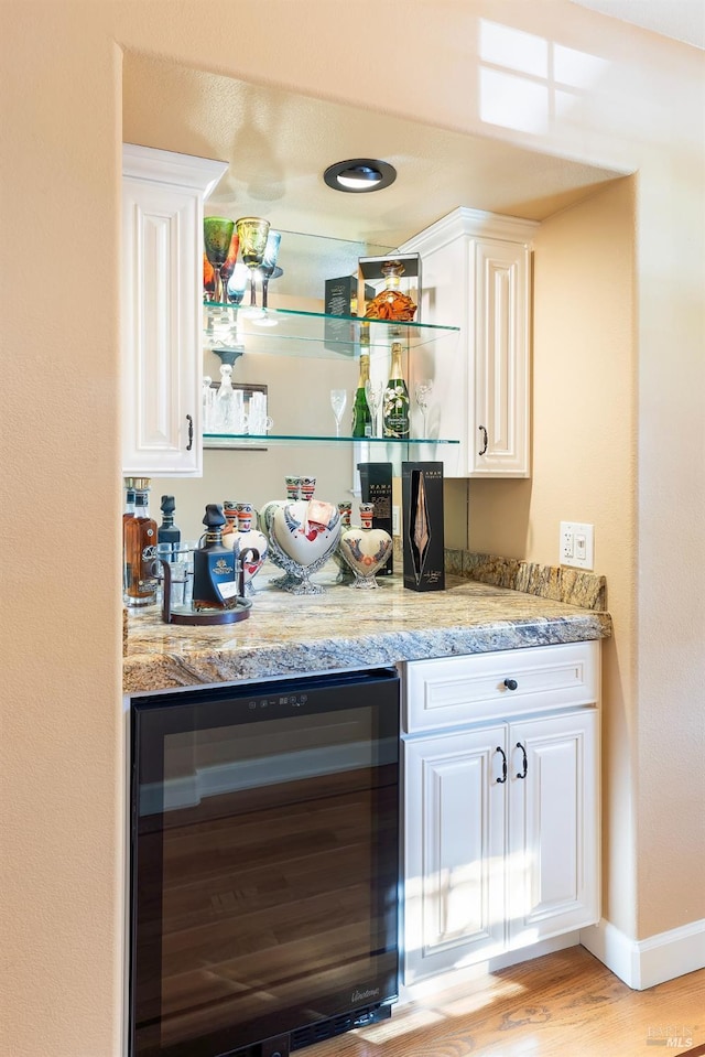 bar with baseboards, a dry bar, wine cooler, and light wood-type flooring