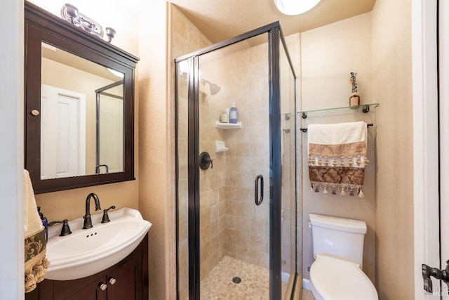 bathroom with vanity, toilet, and a shower stall