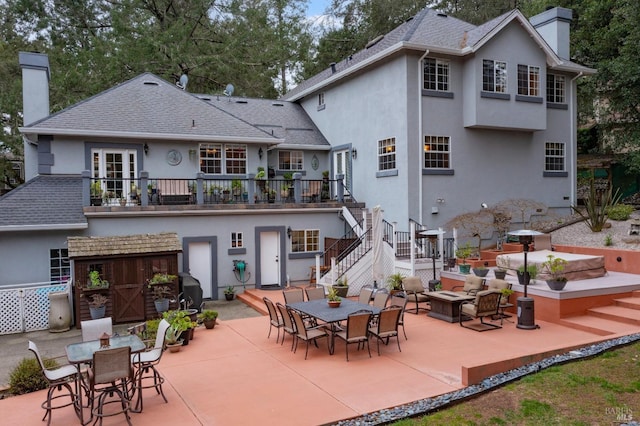 rear view of property with outdoor dining space, a chimney, stucco siding, and a patio