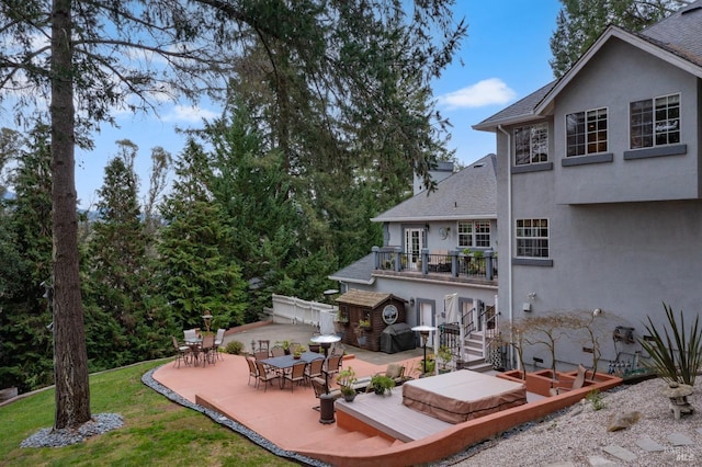 rear view of house featuring stucco siding, stairway, roof with shingles, and a patio area