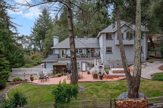 back of property featuring fence, stucco siding, stairway, and a chimney
