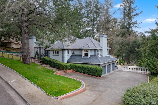 view of front of house featuring driveway, a chimney, fence, an attached garage, and a front lawn